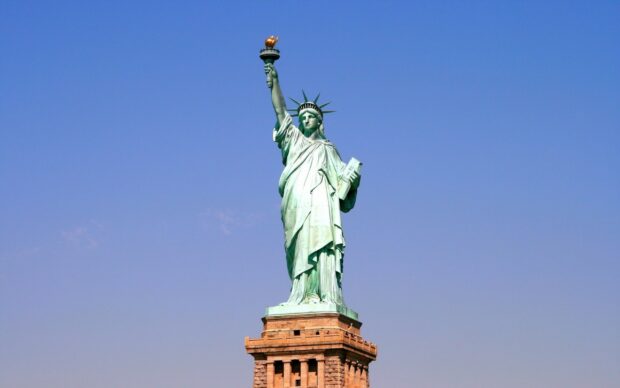 The Statue of Liberty stands against a clear blue sky in this impressive view, 2K PC Wallpaper