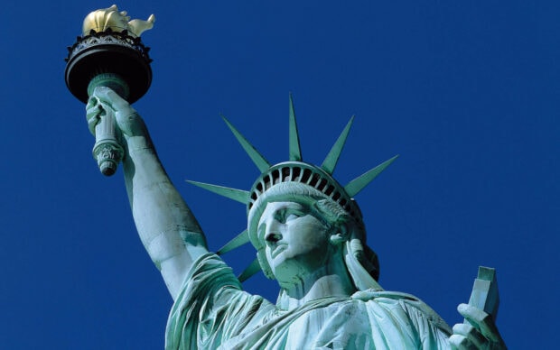 The Statue of Liberty holds a torch against a clear blue sky, HD Desktop Wallpaper