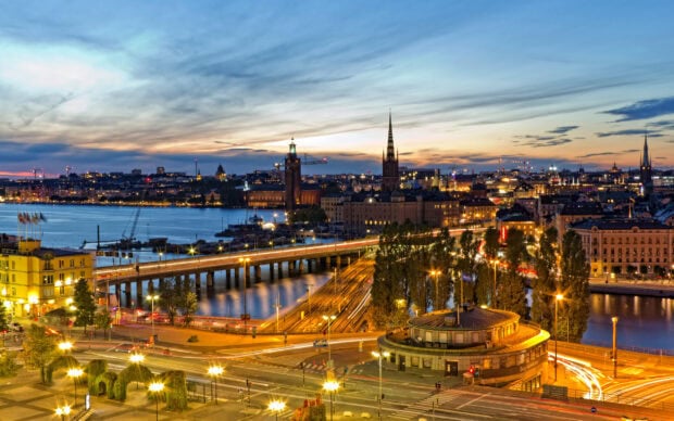 Evening cityscape of Stockholm with illuminated buildings and bridges over water at dusk