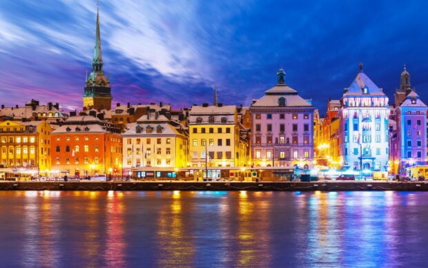 Historic Stockholm buildings reflected in calm water during vibrant evening sky