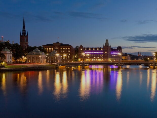 Historic Stockholm cityscape with river reflections at dusk and illuminated buildings