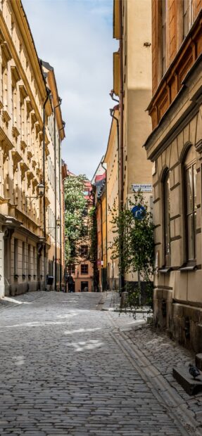 Narrow cobblestone street with old buildings in Stockholm city center street sign visible
