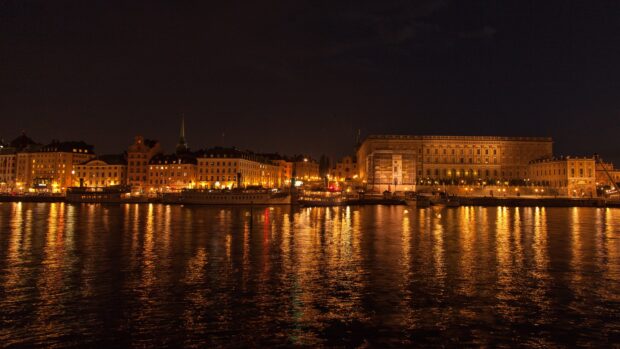 Historic buildings in Stockholm reflecting golden lights on the water at night