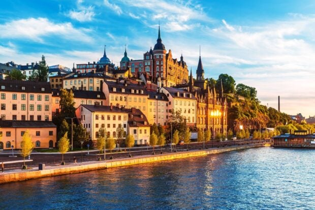 Historic buildings in Stockholm cityscape by waterfront at sunset with clear sky
