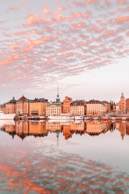 Vibrant Stockholm skyline reflecting in calm water under orange clouded sky
