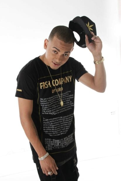A man wearing a black printed shirt and holding a black hat in a bright setting showcasing Ozuna wallpapers, 2K Desktop Wallpaper