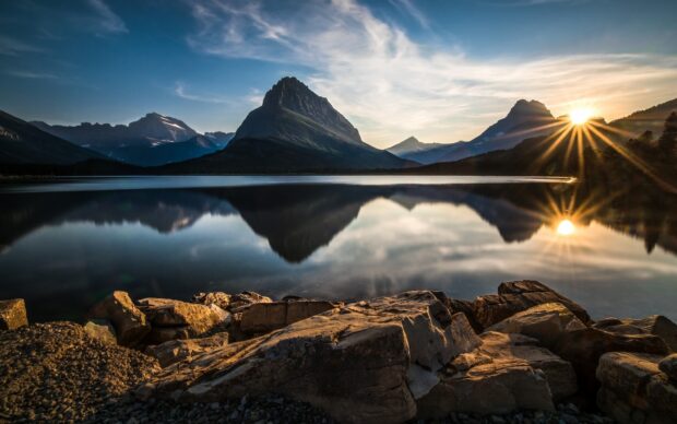 A stunning sunrise reflects off the lake surrounded by rocky mountains in Glacier National Park, HD Desktop Wallpaper