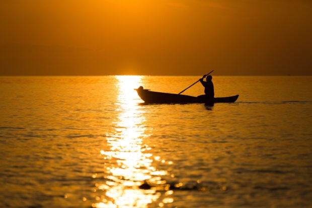 A person paddles a canoe across calm waters during sunset in Malawi, HD Desktop Wallpaper