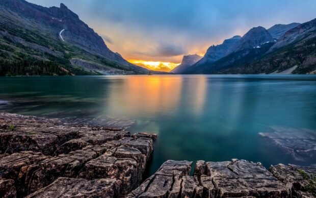 The Montana Wallpapers capture a calm lake reflecting the surrounding rocky mountains at sunset, HD Desktop Wallpaper