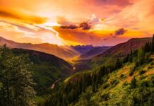 A vibrant sunset illuminates the Montana valley with lush forests and flowing river, 2K Desktop Wallpaper