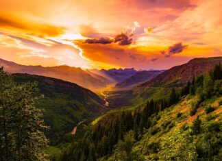 A vibrant sunset illuminates the Montana valley with lush forests and flowing river, 2K Desktop Wallpaper
