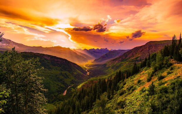 A vibrant sunset illuminates the Montana valley with lush forests and flowing river, 2K Desktop Wallpaper