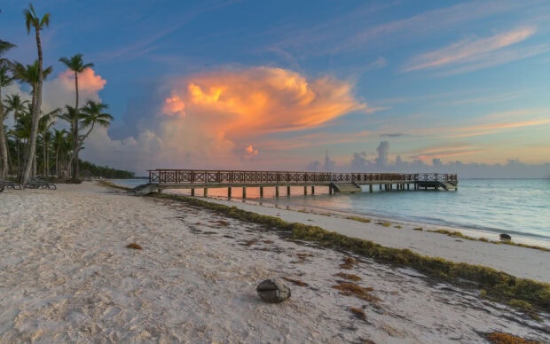 A wooden pier extends into calm ocean waters at sunset in the Dominican Republic, HD Desktop Wallpaper