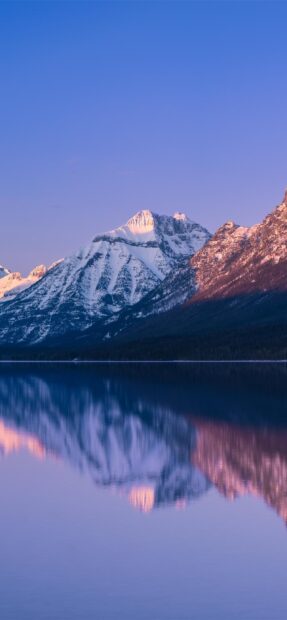The snow covered mountain in Glacier National Park reflects peacefully on the calm lake at sunset, 2K Mobile Wallpaper