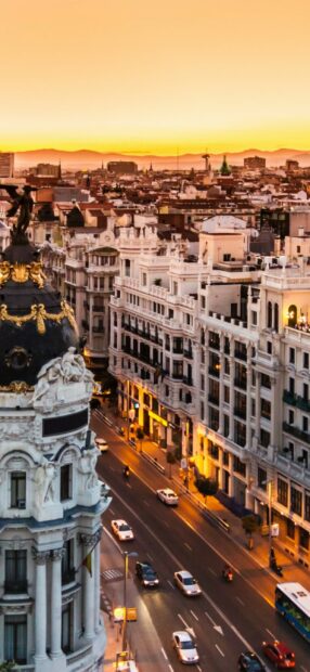 A sunset view captures the vibrant Spain cityscape with historic architecture and busy streets, 2K Mobile Wallpaper