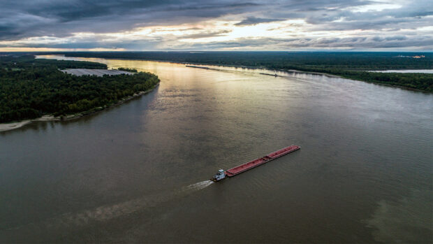 A cargo boat is traveling along the Mississippi River under a cloudy sky at sunset, HD Desktop Wallpaper