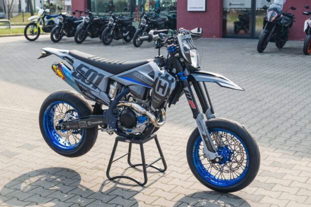 A supermoto bike with blue rims and number 501 parked on a stand outdoors