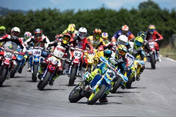 A group of supermoto riders competing on a racetrack during a race event