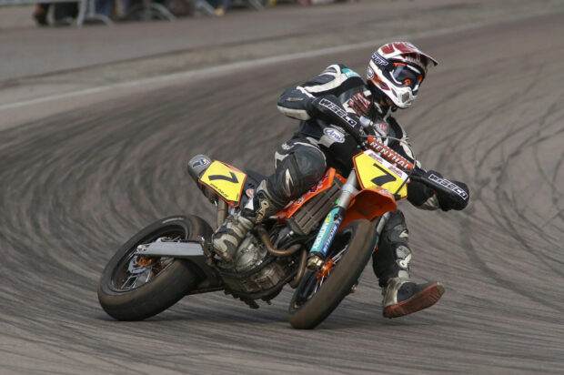 A supermoto rider leaning into a sharp turn on a race track