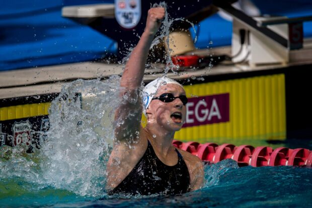 A swimmer celebrating victory with raised fist in a competitive swimming pool