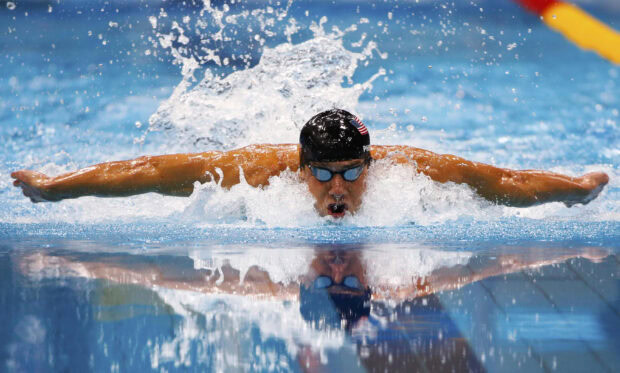 A swimmer performing butterfly stroke in a pool with water splashing around