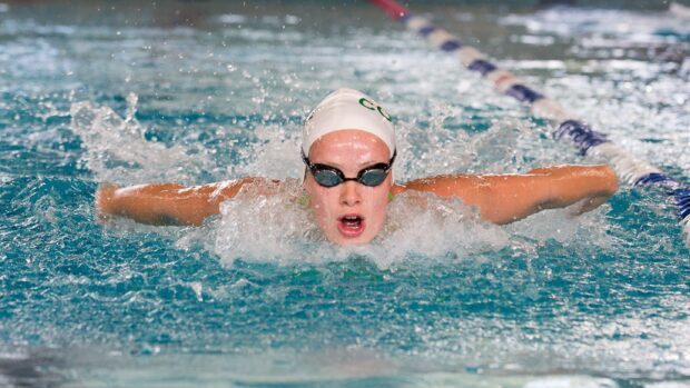 A swimmer wearing goggles and swim cap performing butterfly stroke in the pool
