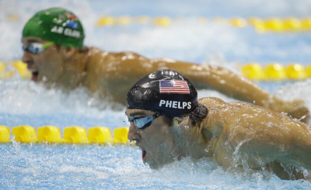 A competitive swimmer performing a butterfly stroke in a swimming pool during a race