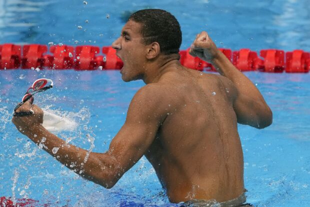 A swimmer celebrating a victory with a clenched fist in a competition swimming pool