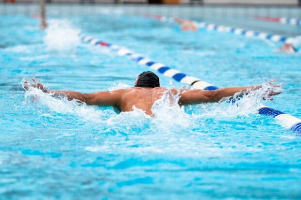 A swimmer performing butterfly stroke in a swimming pool during a race