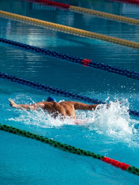 Swimmer performing butterfly stroke in a clear pool during a competitive swimming race