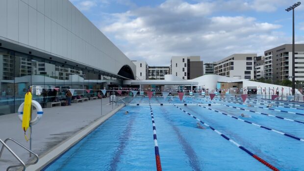 Outdoor swimming pool with multiple lanes and swimmers practicing in the water