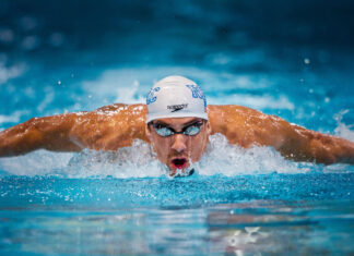 Male swimmer performing butterfly stroke in a swimming pool with intense focus