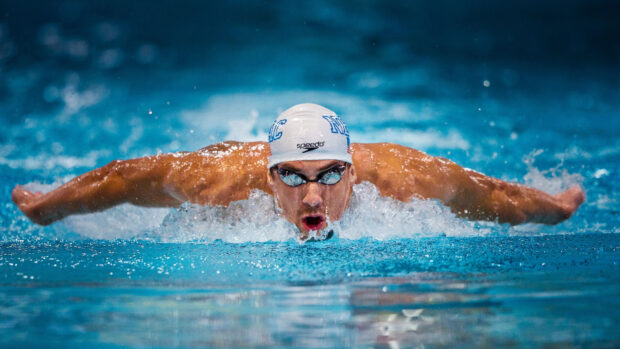 Male swimmer performing butterfly stroke in a swimming pool with intense focus