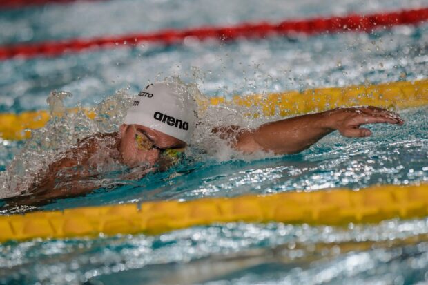 Swimmer performing a freestyle stroke in a swimming pool during a competition