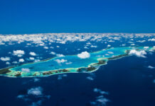 Aerial view of Tahiti island and surrounding turquoise waters under a bright blue sky with scattered clouds
