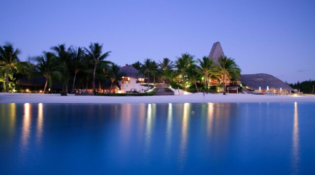 Tropical Tahiti resort with palm trees and serene water reflections at dusk