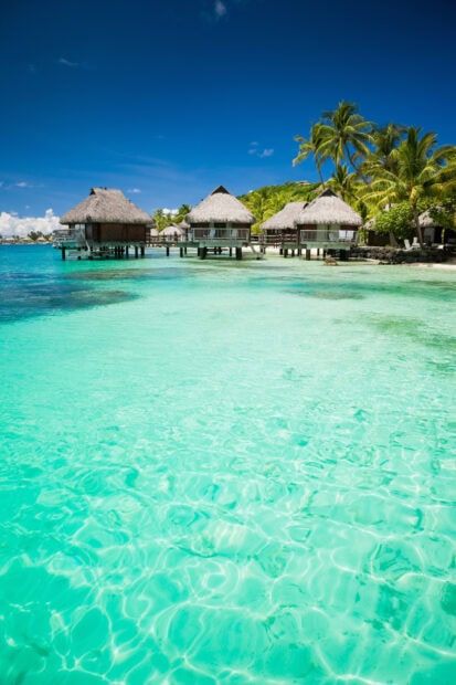 Clear turquoise water and tropical huts in Tahiti paradise
