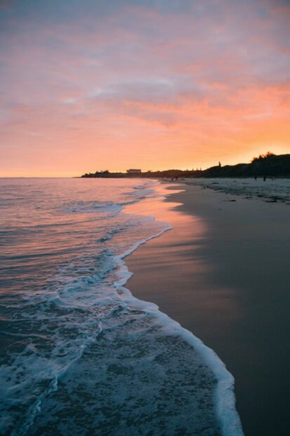 Calm ocean waves gently washing the sandy shore of Tahiti at sunset