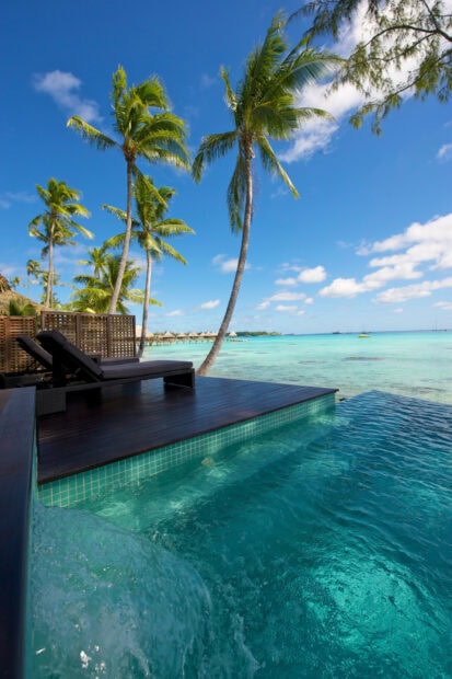 Tropical Tahiti scene with palm trees and clear turquoise water by the pool