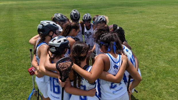 A group of lacrosse players wearing helmets and uniforms in a team huddle on the field, 4K Desktop Wallpaper