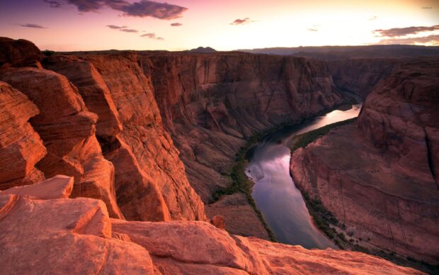 A scenic view of the Colorado River winding through red rock canyon walls at sunset