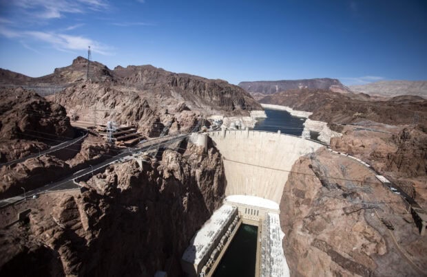 A view of the Colorado River dam nestled between rocky cliffs under a clear blue sky