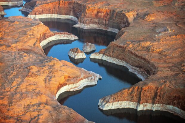 A winding canyon landscape along the Colorado River showcasing layered rock formations and deep blue water