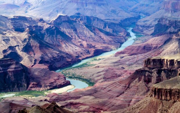 A winding river flowing through rocky canyon landscape with colorful layered cliffs