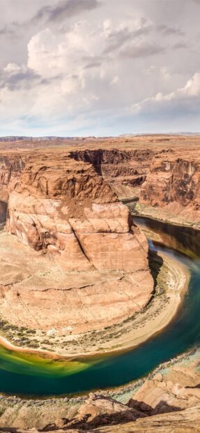 The Colorado River winding through red rock canyon landscape under cloudy sky