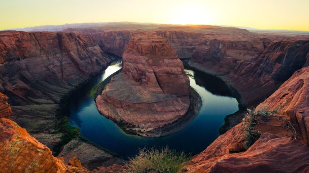 A scenic view of the Colorado River flowing through a deep canyon at sunset