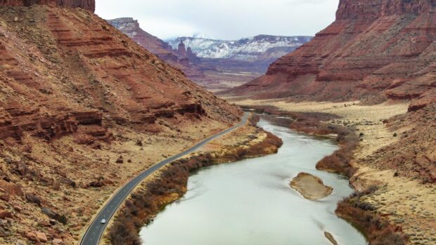 A winding river flowing through the Colorado landscape with surrounding rocky cliffs and a road