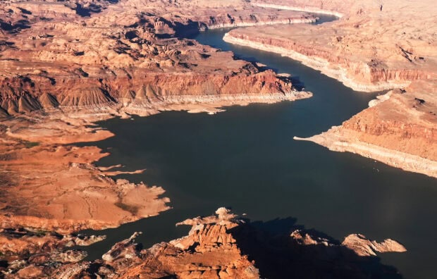 The Colorado River flows through the arid landscape of red rock formations and rugged terrain