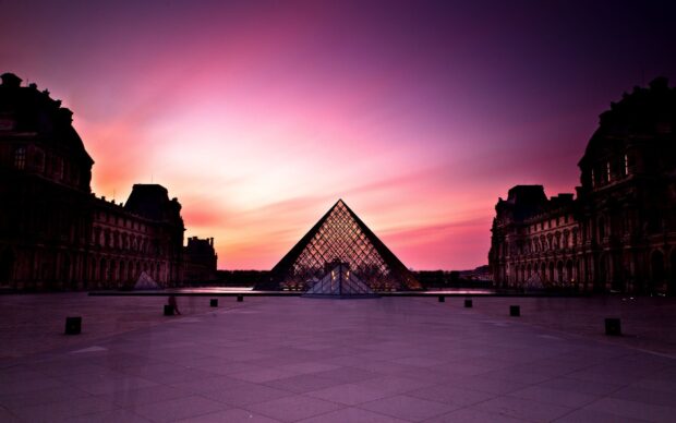 The Louvre glass pyramid with sunset sky in Paris cityscape