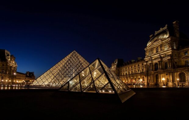 The Louvre pyramid and museum buildings illuminated at night in Paris
